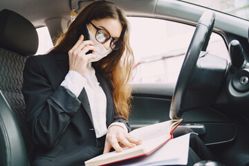 Businesswoman in a black mask sitting inside a car