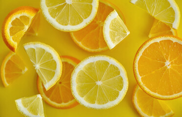Lemon and orange slices on yellow glass background