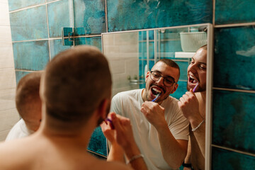 Happy gay couple brushing teeth in bathroom