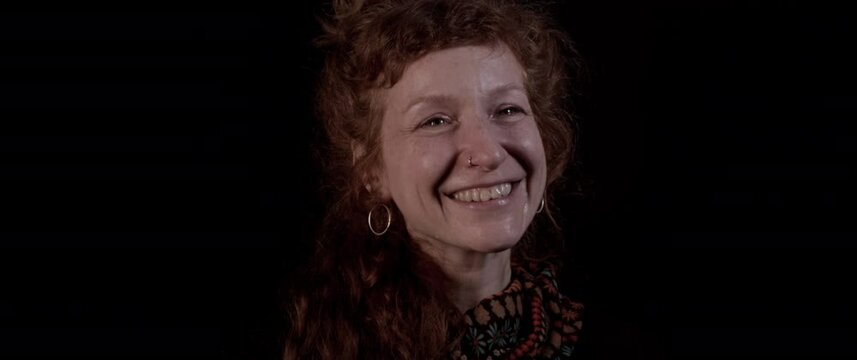 Red curly hair woman laughs with teared up eyes