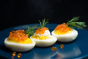 eggs stuffed with red caviar tasty and healthy serving as in a restaurant on a blue plate the best...