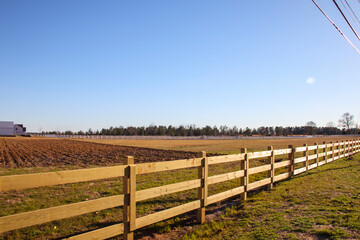 Fototapeta na wymiar A brown wooden fence on a farm and a clear blue sky day