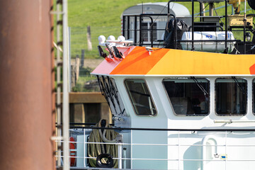 Schiff mit orangem Dach fährt von der Nordsee in den Kanal unter einer Brücke durch