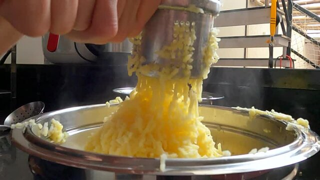Woman smashing potatoes to make gnocchi. Real person in your home making typical Italian food.