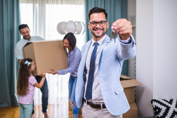 Happy family moving into their new home. Real estate agent showing apartment keys and smiling.