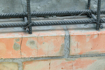 Frame is knitted from metal reinforcement. Corrugated metal rods, flexible wire for binding. Brick wall.