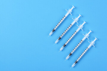 Five new syringes on a blue background with copy space.