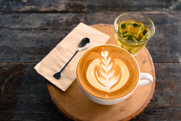 Cup of latte art coffee and hot tea on wooden table