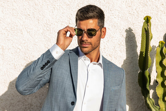 Fototapeta Modern businessman. Confident young man in fashionable suit and sunglasses posing outdoor, relaxing.