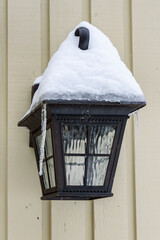 Cold winter, snow and ice covered black light fixture on an exterior wall
