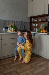 Young mother hugs her little son the kitchen. Family wellness inside the home.