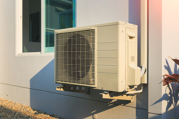 Condenser unit or compressor outside home or residential building. Unit of central air conditioner (AC) or heating ventilation air conditioning system (HVAC). Electric fan and refrigerant pump inside.