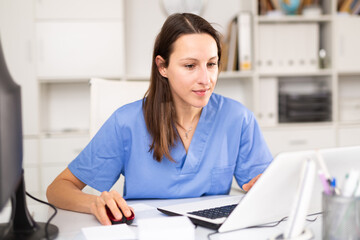 Woman doctor sitting at workplace with computer in her office