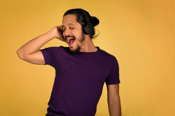 Portrait of man using headphone with yellow background