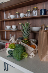 Paper bag with groceries the kitchen table. String bag shopping with vegetables and fruits.