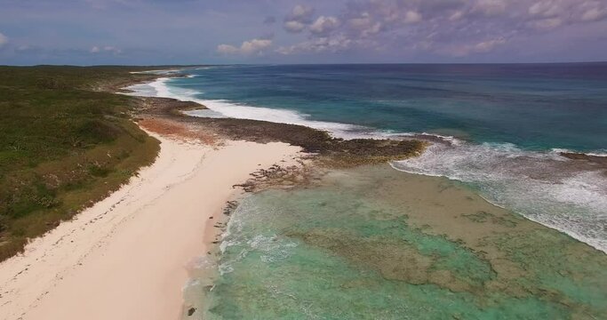 Aerial view of a deserted beach, coral formations and turquoise waters along the coastline on the Atlantic Ocean side of Cat Island, Bahamas.