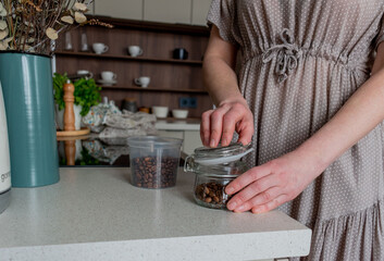 Senior woman pours coffee from plastic container into glass jar. Zero waste concept.