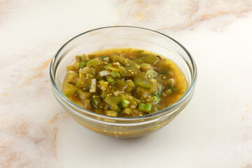 Cooked green tomatillo sauce with green onions in glass ingredient bowl to be used for topping in dish