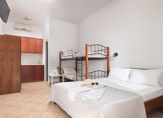 White modern interior of family suit bedroom with classic double bed, bunk bed with metal stairs,...