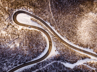 High angle aerial view drone image on the curved serpentine road trough the trees and forest in mountain range with white snow in winter day near Knjazevac in Serbia - Travel journey vacation concept