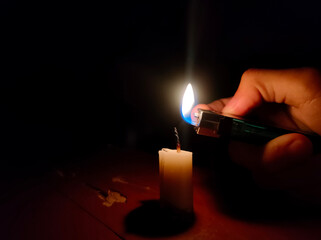 hands light a candle with a gas lighter