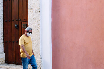 Older man wearing protective mask walking down the street