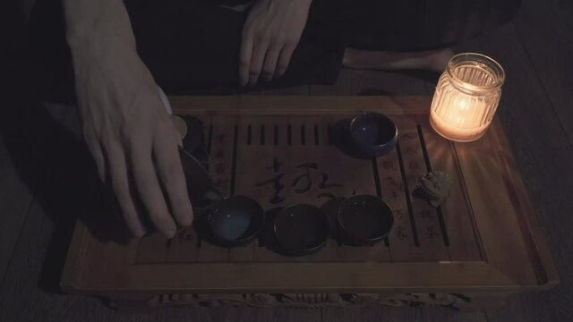 Tea master pours tea into small, clay cups. The man then pours the drink over a clay frog figurine. The concept of Chinese and Japanese tea ceremonies, hobbies and lifestyle