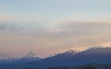 Obraz premium Tramonto di luce e foschia sulle cime innevate dell’appennino