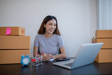 Small business entrepreneur SME freelance,Portrait young woman working on laptop at home office, online marketing packaging delivery box, SME e-commerce concept