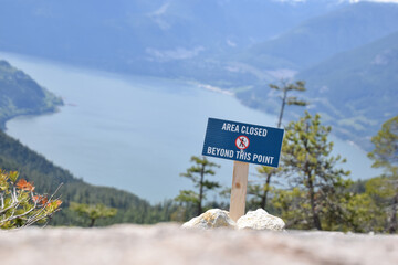Area closed sign for mountain slope on the trail, overlooking the lake background