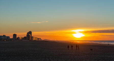 People walking on Oostende (Ostend) beach at sunset by the North Sea, Belgium.
