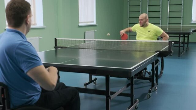 A man in a wheelchair plays ping pong. People with disabilities play table tennis. Rehabilitation of the disabled. Paralympic sport.