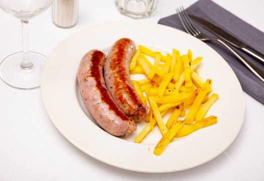 Close up of tasty fried pork sausages with french fries, served on plate