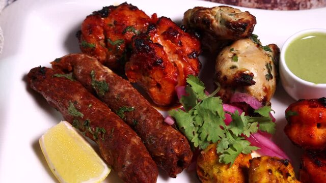 Mixed grill kebab chicken mutton beef prawn fish mint sauce lemon pickled onion bread basket chapati naan tandoori paratha dal lentil fry tadka copper pot on white dish over rustic background 