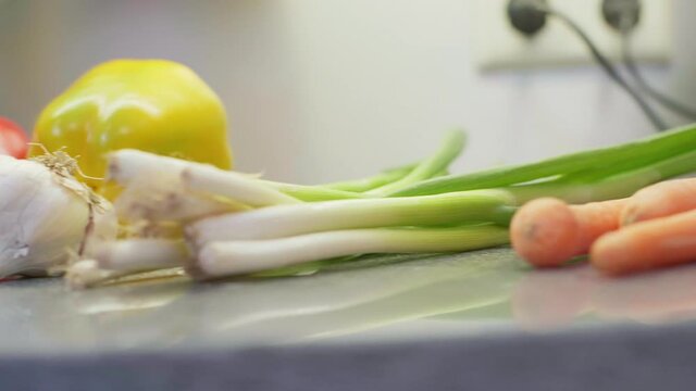 4K Delicious fresh vegetables carrots, peppers, garlic and leek laying in a kitchen. Smooth professional slow motion cooking; Slider pan movement; Shallow depth.