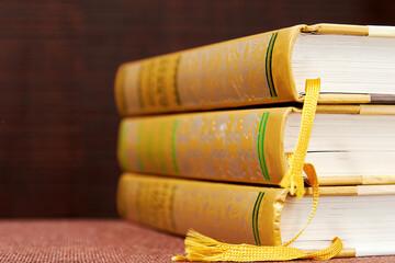 Stack of three hardcovered books on the bookshelf in the library. Novel and poetry literature. Copy space for your text