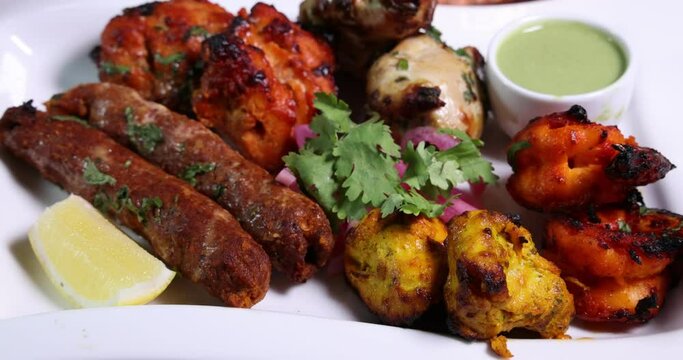 Mixed grill kebab chicken mutton beef prawn fish mint sauce lemon pickled onion bread basket chapati naan tandoori paratha dal lentil fry tadka copper pot on white dish over rustic background