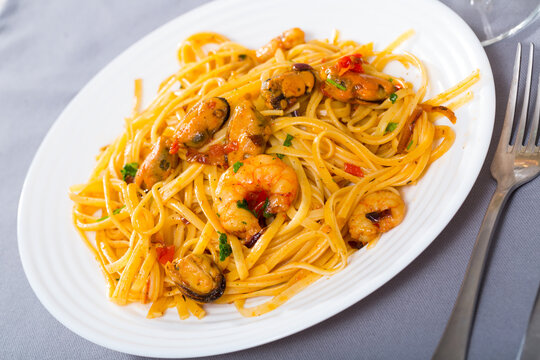 Image of delicious pasta of shrimps, mussels and greens at plate