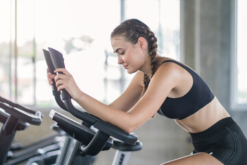 Obraz premium Beautiful sport woman working out on exercise bike at sport health club