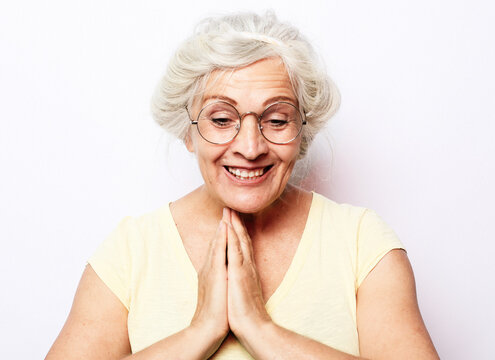 Surprised happy elderly woman looks down and laughing