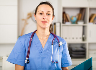 Woman doctor wear white medical uniform and stethoscope with blue folder of documents in clinic