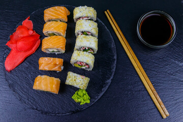 Set of sushi rolls on a black stone slate. Top view