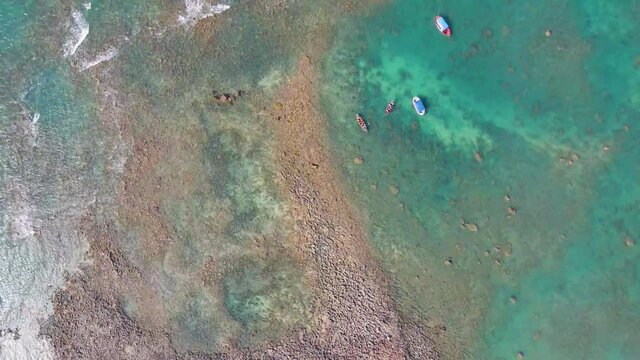 Small boats near sandy coastline in Saint Martin island, aerial top-down view