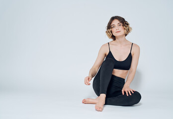 Fototapeta premium Woman in sportswear sits on the floor in a bright room and t-shirt leggings