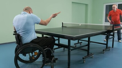 A man in a wheelchair plays ping pong. People with disabilities play table tennis. Rehabilitation of the disabled. Paralympic sport.