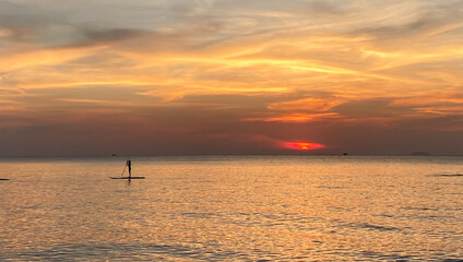 Silhouette of Stand Up Paddle board on the beach at sunset. Surfer and ocean. Side view.