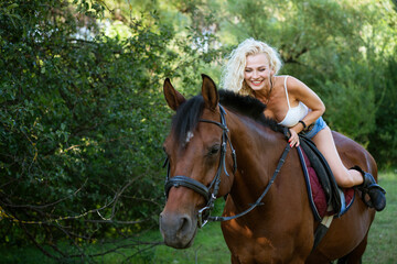 Beautiful happy woman with horse in summer park