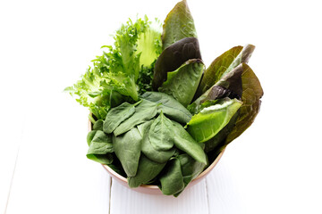 Bowl with salad leaves of spinach, lettuce, romaine on white wooden background