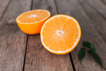 Halves of orange fruit on gray wooden background. Orange pulp and green leaves