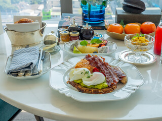 Breakfast set, fried egg, bacon, cereal, milk and pastry on elegant ceramic dish, served in luxury hotel